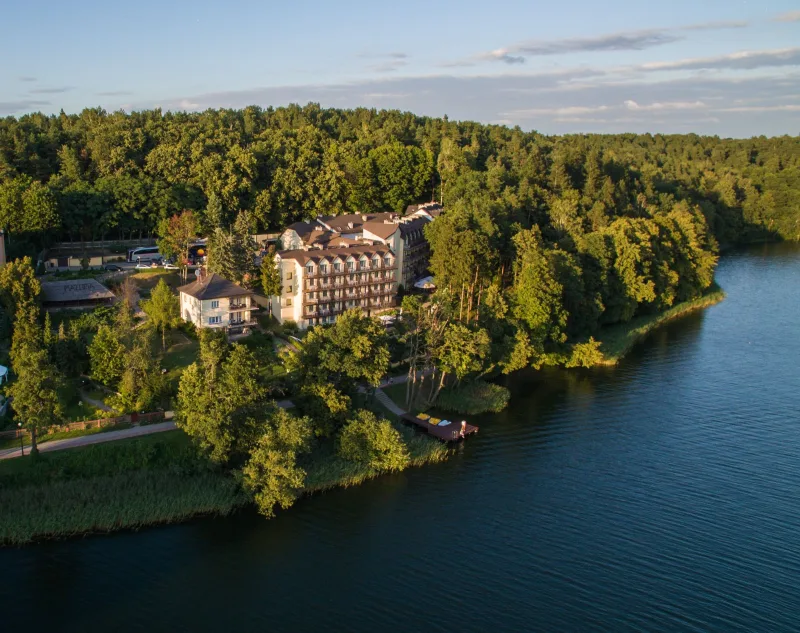 Widok z lotu ptaka na jezioro i hotel pośród lasu