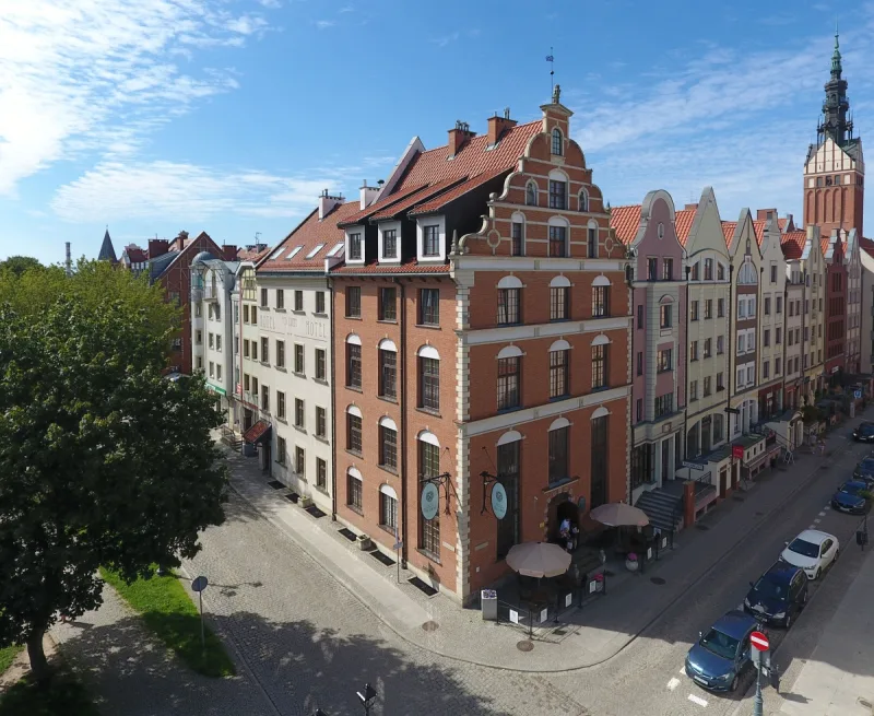 Budynek hotelu z zewnątrz z czerwonej cegły i widok na uliczkę Starego Miasta w Elblągu z kamienicami