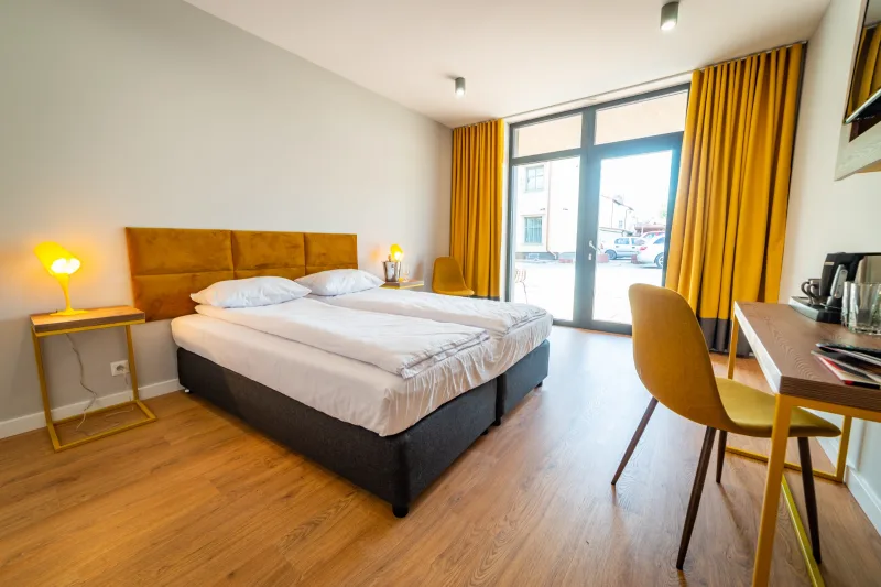 Wnętrze apartamentu, widok m.in. na łóżko i okno balkonowe